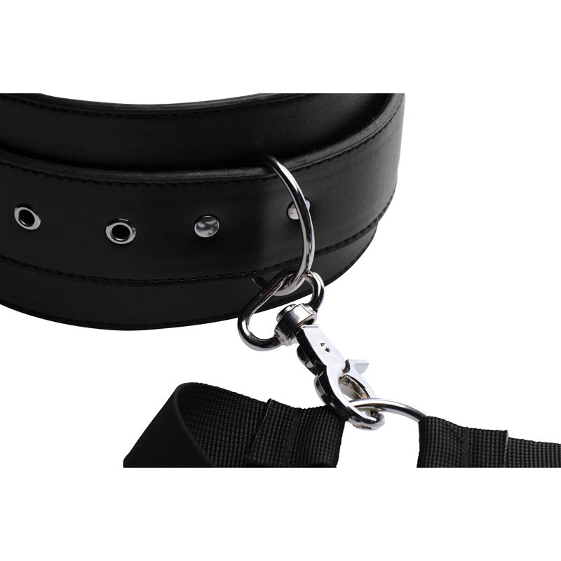 Close-up of a black padded thigh cuff with metal eyelets, a D-ring and a silver clip attaching the nylon strap